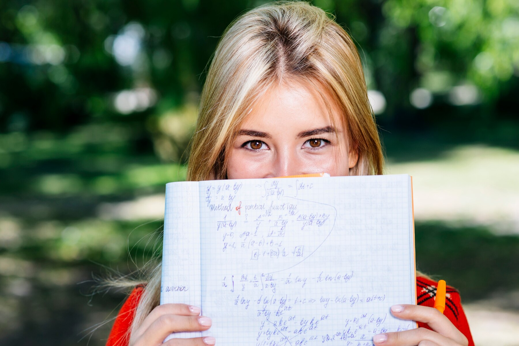 Grade schooler showing a notebook with solutions to math word problems