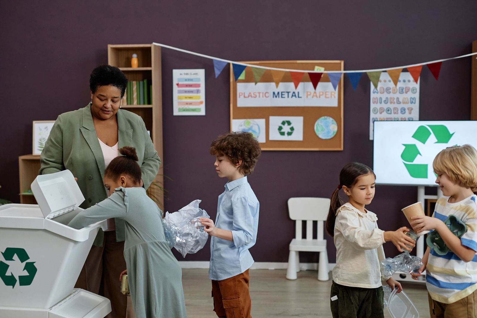 Side view portrait of kids standing in line to recycling bin during cleanup as one of transition activities for preschoolers