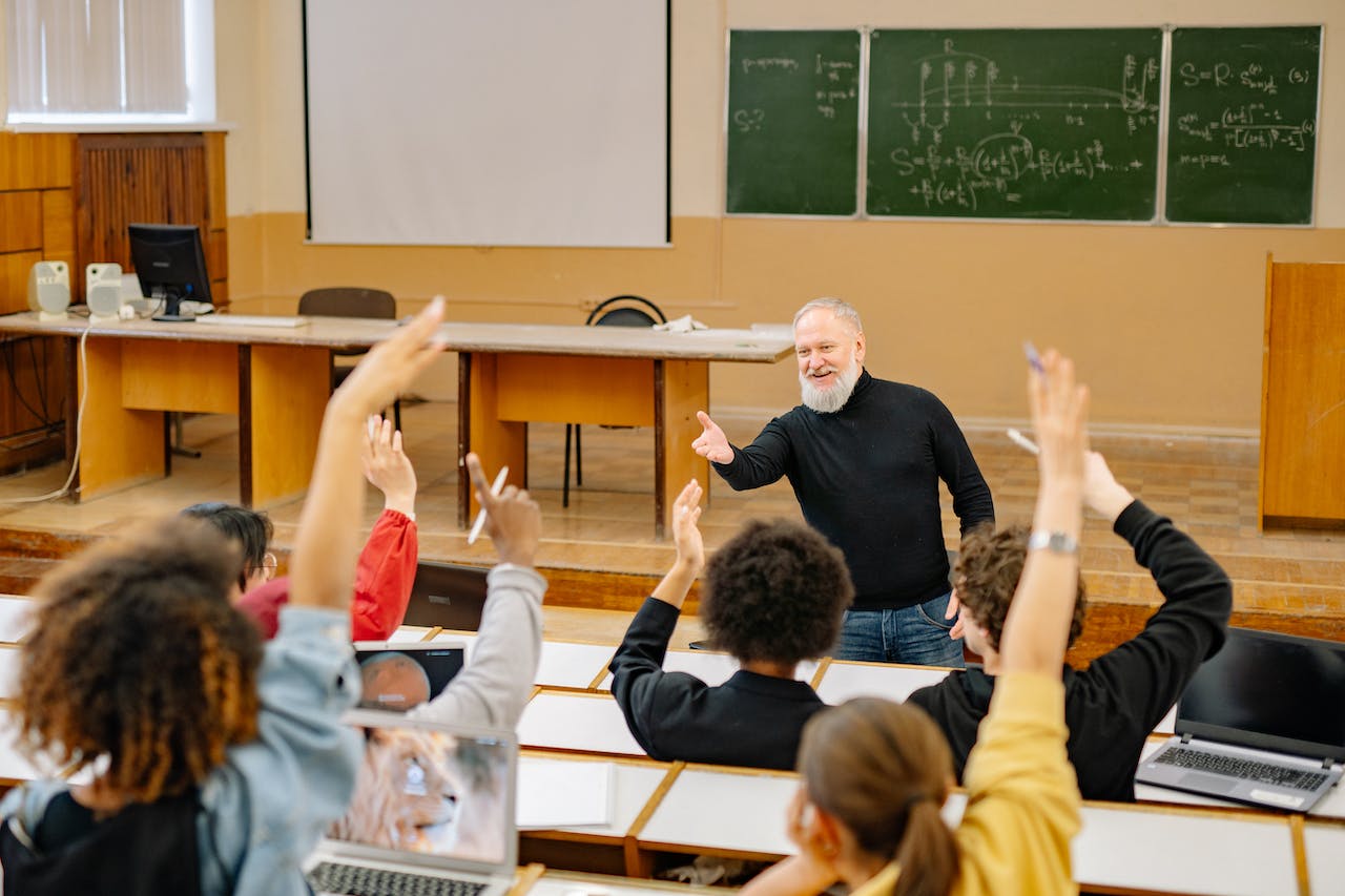 an engaged classroom with students raising hands